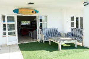 eine Terrasse mit 2 Stühlen, einem Tisch und einem Surfbrett in der Unterkunft Villa 43, The Estuary Country Estate, Port Edward, KZN South Coast in Port Edward