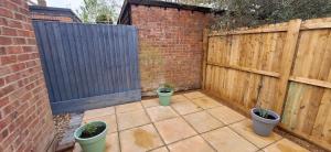 a patio with two potted plants next to a wooden fence at The Hollies in Briston