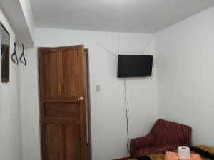 Habitación con puerta y TV en la pared en Aparthotel ANDESITA CUSCO, en Cusco