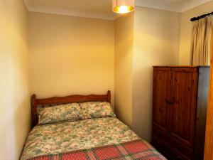 1 dormitorio con 1 cama y armario de madera en Celyn Bach Llangrannog, en Llwyn-Dafydd