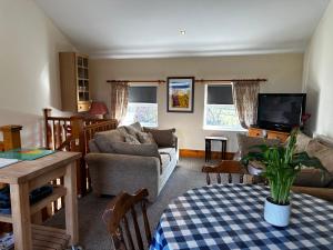 a living room with a couch and a tv at Celyn Bach Llangrannog in Llwyn-Dafydd