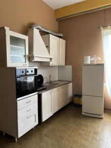 a kitchen with white cabinets and a stove top oven at Ostello Bellavita in Castelnuovo di Garfagnana