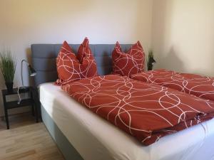 Una cama con almohadas rojas y blancas. en Bischofswerda Ferienwohnung Familienfreundlich Seniorengerecht, en Bischofswerda