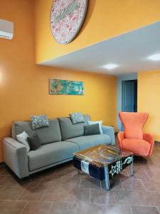 un salon avec un canapé et une horloge au mur dans l'établissement La magnanerie colorée. (5 personnes, 3 chambres), à Ancône