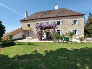 an old stone house with a wreath of purple flowers at Crisoline in Longwy-sur-le-Doubs
