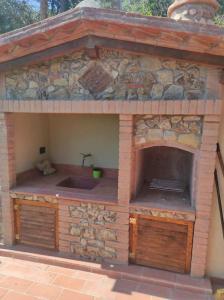a outdoor kitchen with a stone building with a sink at Il giardino fiorito in Santa Luce