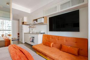 een oranje bank in een woonkamer met een flatscreen-tv bij Apartamento novo e completo próximo a paulista in Sao Paulo