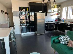 a kitchen with a refrigerator and a green couch at Cosy apartment in front of the sea in Anglet