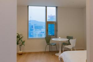 ソウルにある"GRAND OPENED" Maxtyle Guesthouse Dongdaemunのテーブルと椅子、窓が備わる客室です。