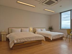 Duas camas num quarto branco com duas janelas em "GRAND OPENED" Maxtyle Guesthouse Dongdaemun em Seul