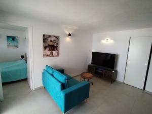 a living room with a blue couch and a television at Résidence La Palmeraie in Le Diamant