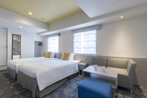 a hotel room with two beds and a couch at Tokyu Stay Suidobashi in Tokyo