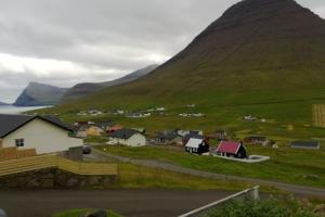 un petit village avec une montagne en arrière-plan dans l'établissement Apartment with a panoramic view, à Viðareiði