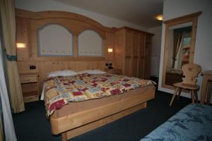 a bedroom with a large bed with a wooden headboard at Garni Eden in Canazei