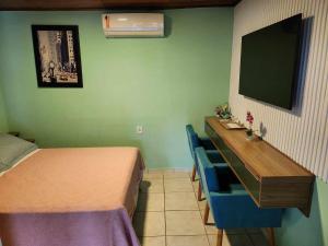 Una habitación con una cama y un escritorio con televisión. en Beto Pousada, en Penha