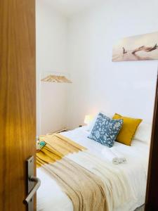 Un dormitorio con una cama blanca con almohadas azules y amarillas en Quarto Duplo em Lisboa - Casa de Anfitrião en Lisboa