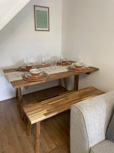 einen Holztisch mit Tellern und Weingläsern darauf in der Unterkunft Cosy home close to M6 motorway in Pemberton