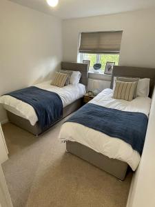 2 Betten in einem kleinen Schlafzimmer mit Fenster in der Unterkunft Cosy home close to M6 motorway in Pemberton