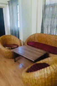 two wicker chairs and a wooden table in a room at Pretty park facing 2 bedroom guesthouse near lohia park Gomtinagar in Lucknow