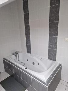 y baño con bañera y azulejos blancos. en Appartement dans Maison en pleine campagne, en Métairies-Saint-Quirin