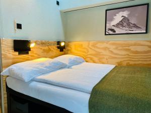 a bedroom with a large bed with white sheets at Peaky Riders Self Check-in Hotel in Zermatt