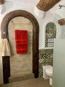 a bathroom with a red towel and a toilet at Cueva Romana, Adults Only Cave House in Cuevas del Campo