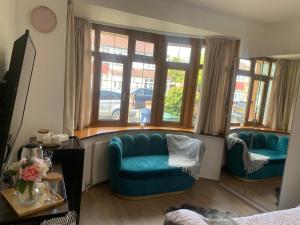 a living room with two blue chairs and windows at mayfair in Northolt