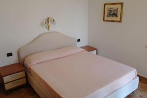 a bedroom with a white bed and a night stand at Bari Sardo Le More Suite 3 in Bari Sardo