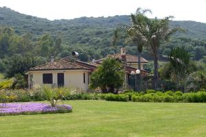 a house in a yard with flowers and trees at Bari Sardo Le More Suite 3 in Bari Sardo