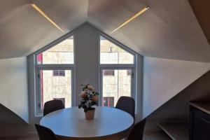 a table with a vase of flowers on it in front of windows at Apartment in Tromsø city center in Tromsø +14 photos