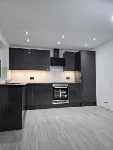 a large kitchen with black cabinets and appliances at Beautiful maisonette in Leeds