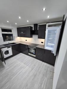 a kitchen with black cabinets and a washer and dryer at Beautiful maisonette in Leeds