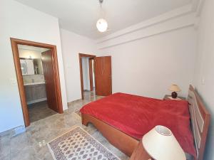 a bedroom with a red bed and a bathroom at Nick's Apartments Evia in Achladi +39 photos