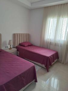 two beds in a bedroom with purple sheets and a window at La PERLA in Hammamet Sud +10 photos