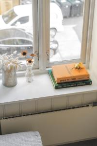 two books sitting on a window sill with flowers at Studio apartment in central Oslo in Oslo