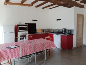 a kitchen with red cabinets and a table with a red table cloth at Les gîtes de Camarel in La Plaine