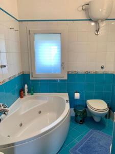 uma casa de banho com uma banheira, um WC e uma janela. em La Terrazza di Nonna Maria em Realmonte