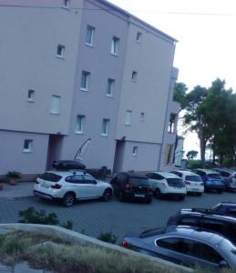 un gruppo di auto parcheggiate in un parcheggio di fronte a un edificio di SARITA Apartments 1 a Makarska