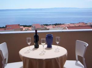 SARITA Apartments 1 في ماكارسكا: طاولة مع زجاجة من النبيذ وكأسين