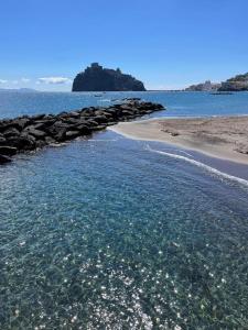 a body of water with a beach with rocks at CASA VACANZE VITTORIA COLONNA in Ischia
