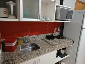 a small kitchen with a sink and a refrigerator at Flat Águas da Serra - com acesso ao rio in Rio Quente
