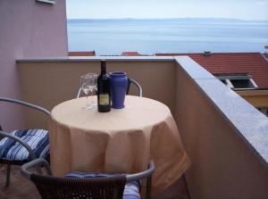 a table with a bottle of wine and glasses on a balcony at SARITA Apartments 1 in Makarska