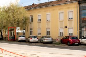 une rangée de voitures garées devant un bâtiment dans l'établissement Apartman Agata,Osijek, self check-in, à Osijek