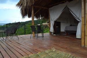 a tent with a bed and chairs on a wooden deck at Encanto Toscano in Quimbaya