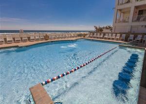 a large swimming pool next to a hotel with a beach at Island Breeze 120A in Virginia Beach