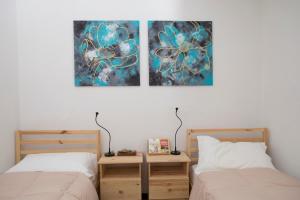 two beds in a bedroom with two paintings on the wall at Madamin locazioni turistiche in Sant' Agata fossili
