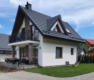 uma casa branca com um telhado preto em Korona Pienin Domki & Apartamenty em Szczawnica
