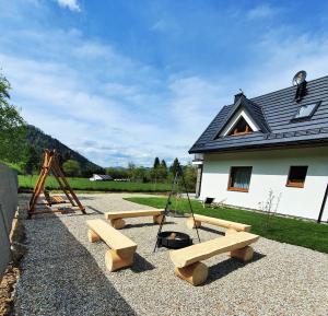 a playground with benches and swings in front of a building at Korona Pienin Domki & Apartamenty in Szczawnica
