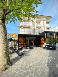 un bâtiment avec une cour dotée de chaises et d'un arbre dans l'établissement Hotel Reale, à Rimini