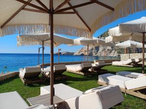 a group of chairs and umbrellas on the beach at Petani Beachside Accommodation in Vovikes